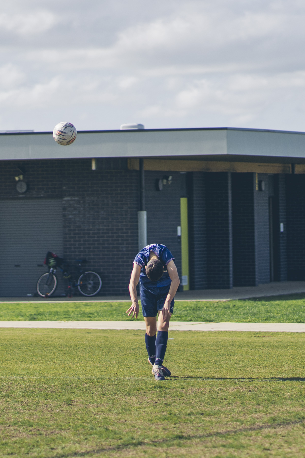 Soccer player throwing a ball near the clubrooms