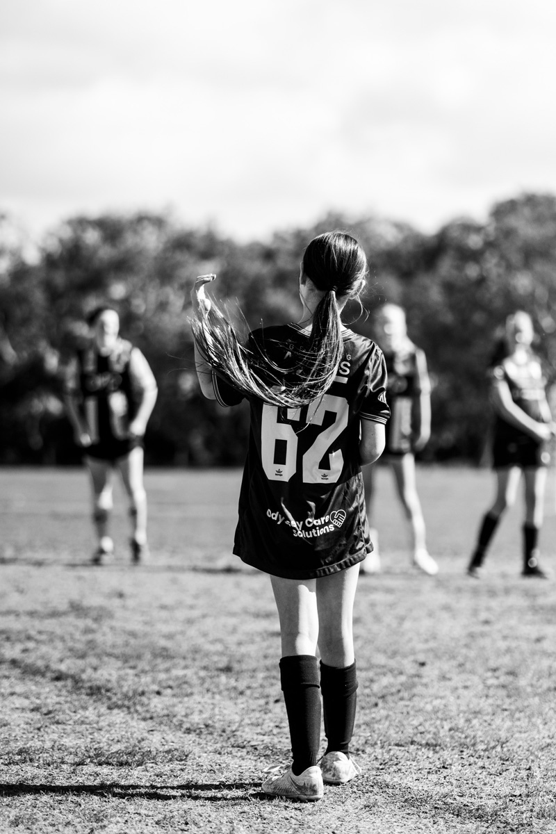 Girls soccer player with her hair flicking mid movement on the field, black and white