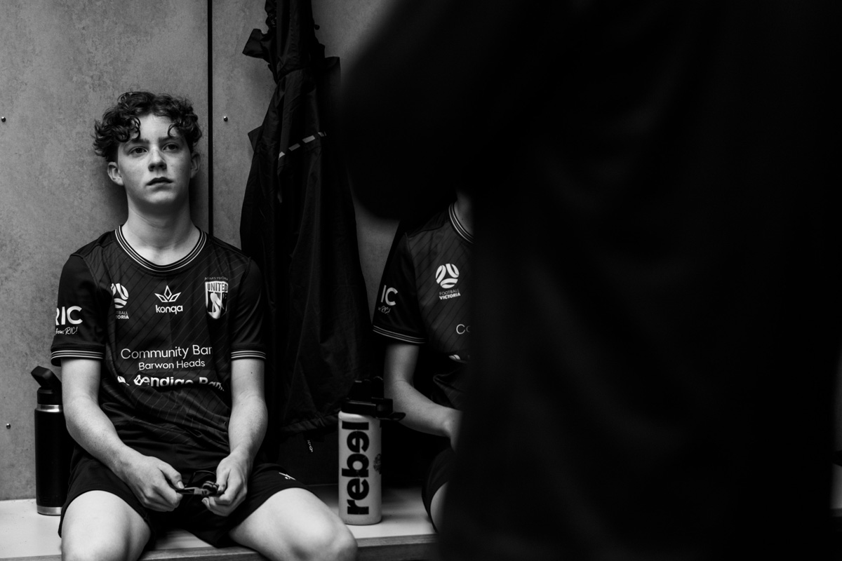 Junior soccer player sitting in the locker room before a match, black and white