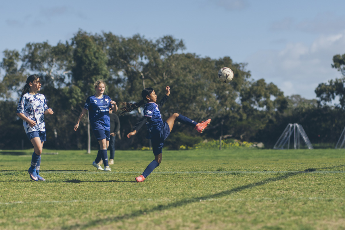 Girls soccer player kicking the ball during a match