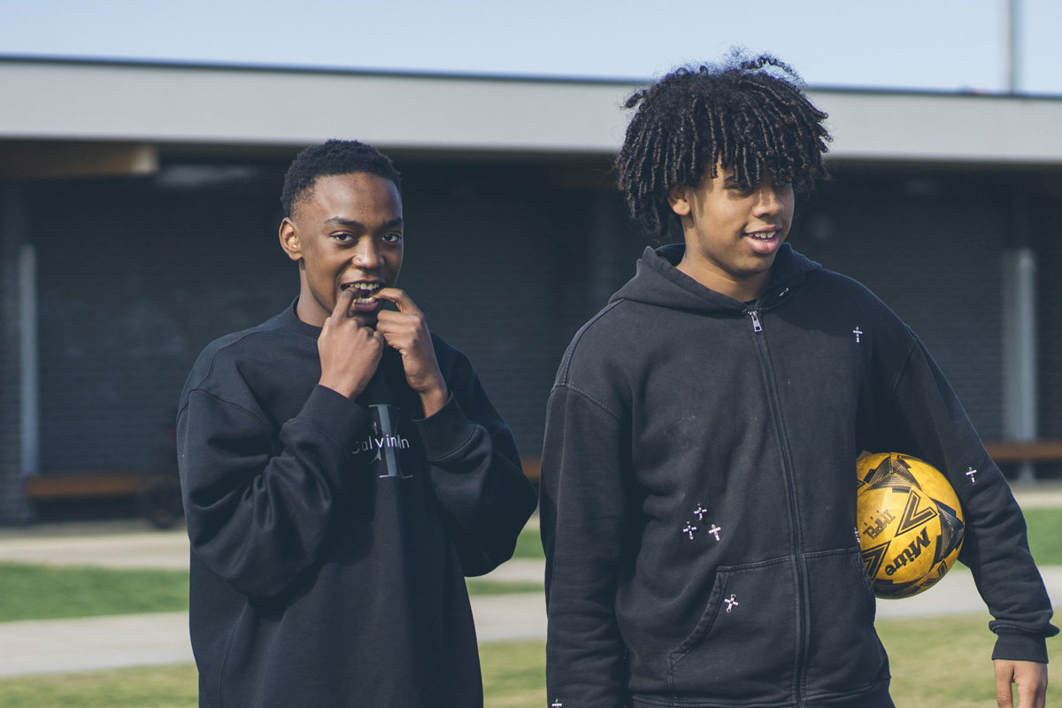 Two teenage soccer players standing together with a ball, casual portrait