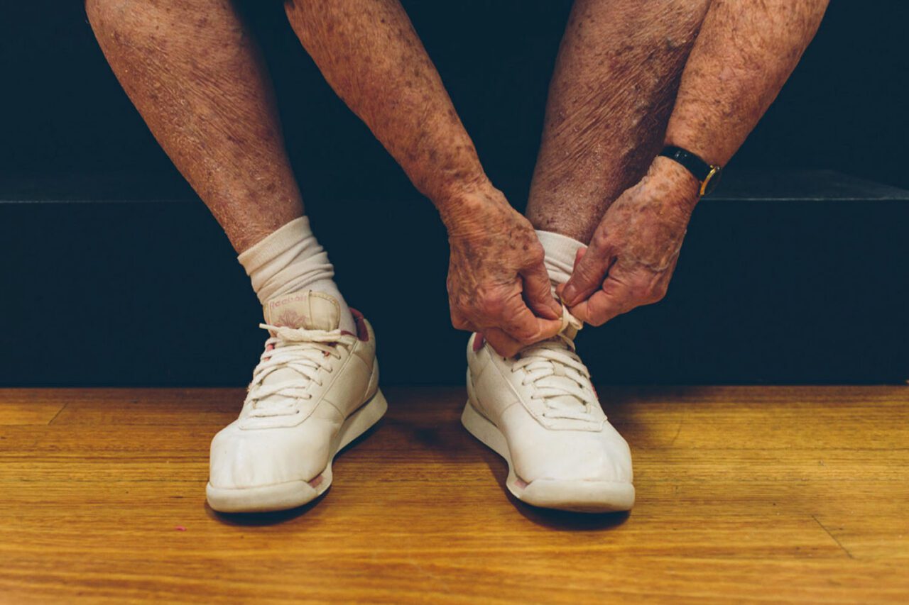 Elderly hands tying white sneaker laces before an exercise class, community photography Geelong