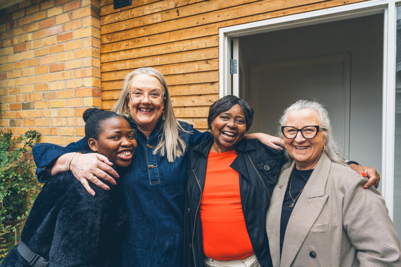 Four women laughing and hugging together outside a Destination Accessible home