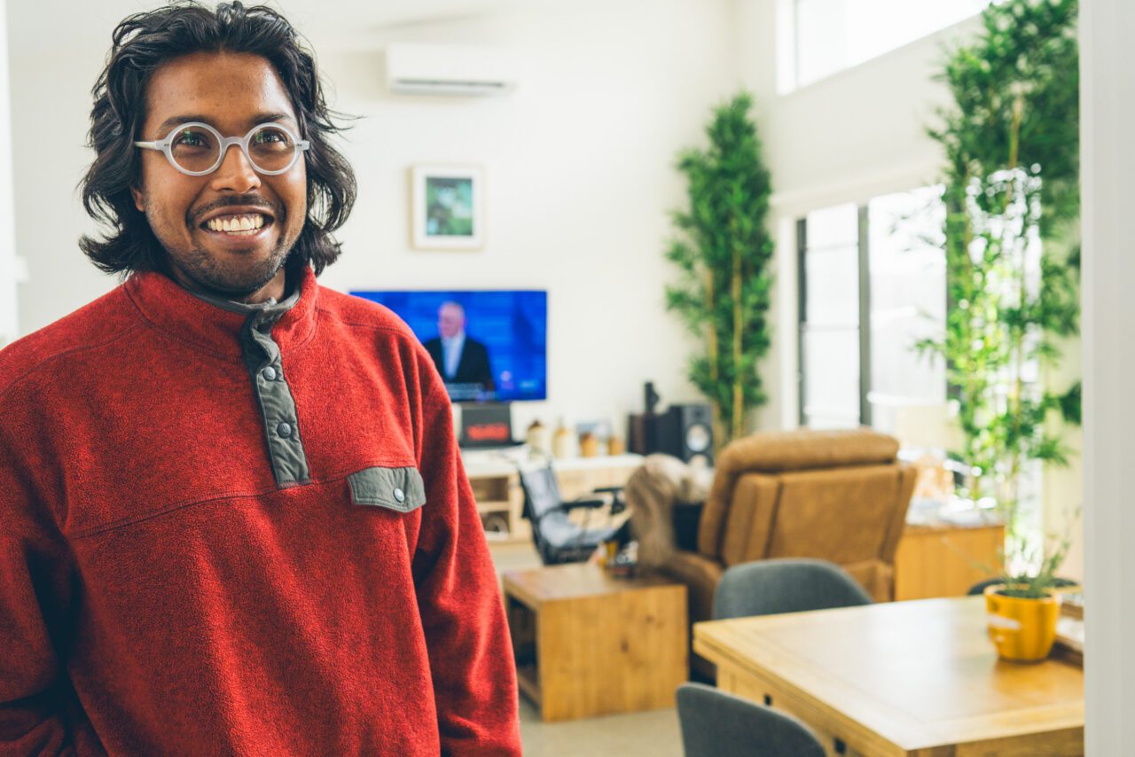 Smiling support worker in a red fleece standing in a bright living room at a Destination Accessible home